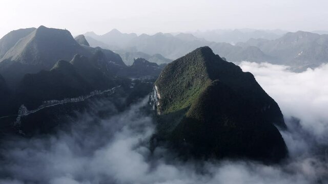 Beautiful Asian karst mountains rising above low clouds, aerial view