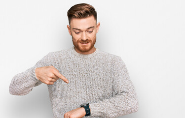 Young redhead man wearing casual winter sweater in hurry pointing to watch time, impatience, upset...