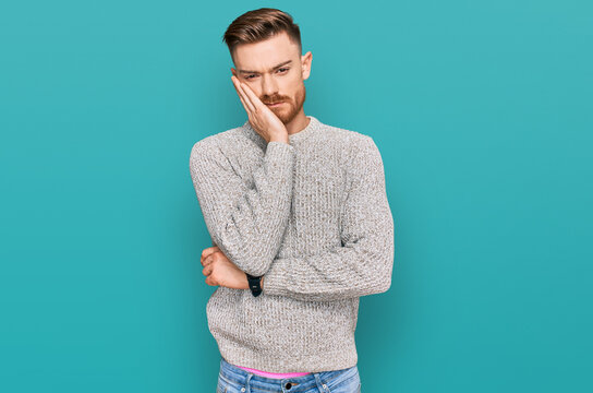 Young redhead man wearing casual winter sweater thinking looking tired and bored with depression problems with crossed arms.