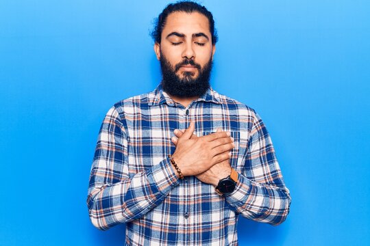 Young arab man wearing casual clothes smiling with hands on chest with closed eyes and grateful gesture on face. health concept.