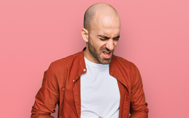 Young hispanic man wearing casual clothes with hand on stomach because nausea, painful disease feeling unwell. ache concept.