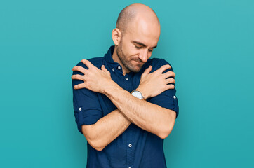 Young hispanic man wearing casual clothes hugging oneself happy and positive, smiling confident....