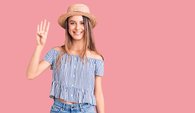 Young beautiful girl wearing hat and t shirt showing and pointing up with fingers number four while smiling confident and happy.