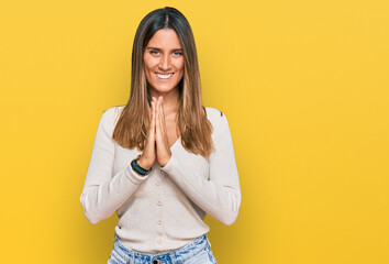 Young woman wearing casual clothes praying with hands together asking for forgiveness smiling confident.