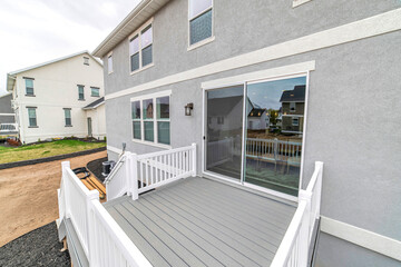 Deck of two storey house with sliding glass door and stairs leading to yard