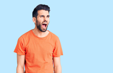 Fototapeta premium Young handsome man with beard wearing casual t-shirt angry and mad screaming frustrated and furious, shouting with anger. rage and aggressive concept.