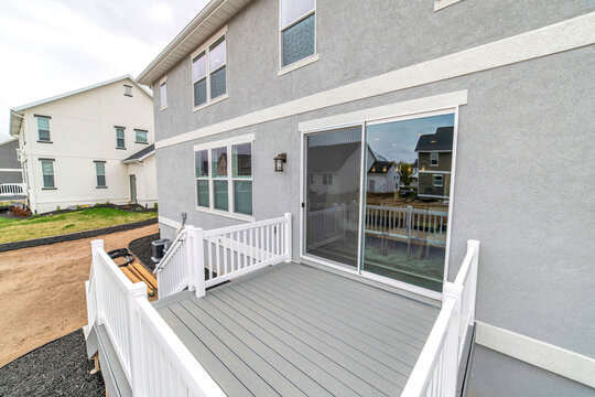 Deck of two storey house with sliding glass door and stairs leading to yard