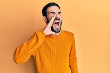 Young hispanic man wearing casual clothes shouting and screaming loud to side with hand on mouth. communication concept.