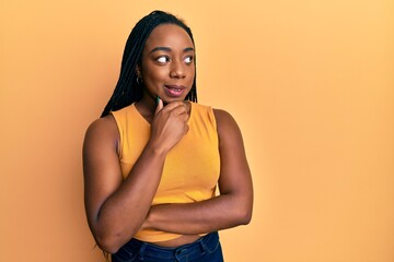 Obraz premium Young african american woman wearing casual clothes with hand on chin thinking about question, pensive expression. smiling with thoughtful face. doubt concept.