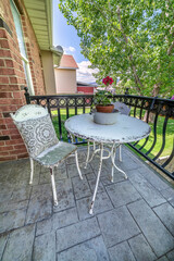 Metal round table and chairs with flowers and pillow at the balcony of a house