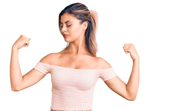 Young beautiful woman wearing casual clothes showing arms muscles smiling proud. fitness concept.