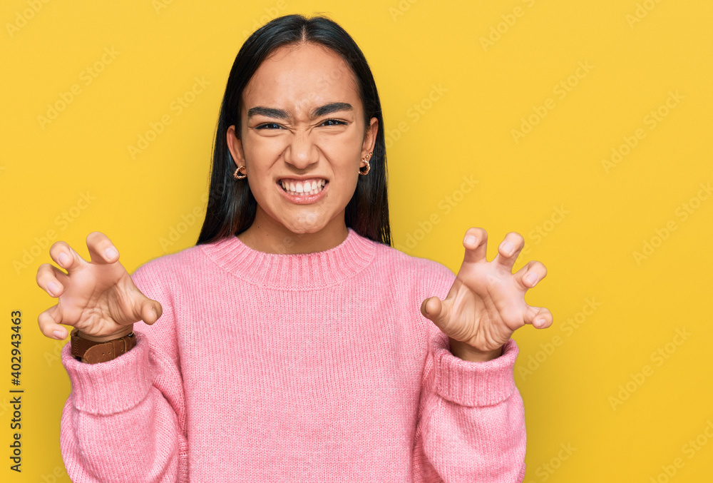 Sticker young asian woman wearing casual winter sweater smiling funny doing claw gesture as cat, aggressive 