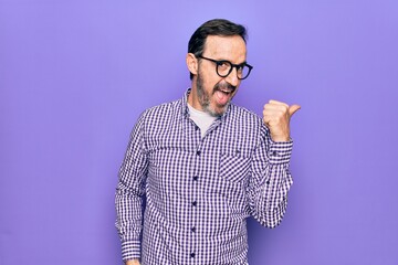 Middle age handsome man wearing casual shirt and glasses over isolated white background pointing thumb up to the side smiling happy with open mouth