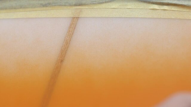Close up slow motion shot of spray painting a surfboard orange
