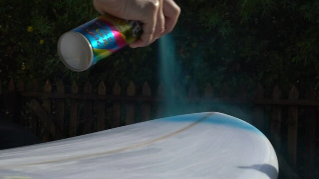 Close up slow motion shot of spray painting a surfboard