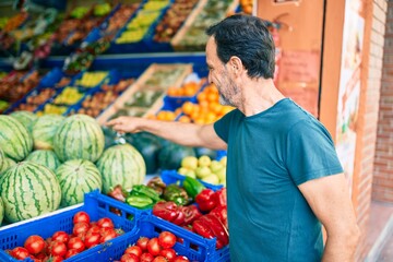 Middle age man with beard smiling happy shopping vegetables at the grocery supermarket