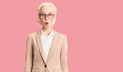 Young blonde woman wearing business clothes and glasses afraid and shocked with surprise expression, fear and excited face.