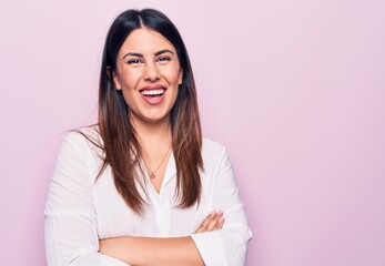 Young beautiful brunette woman wearing elegant shirt standing over isolated pink background happy face smiling with crossed arms looking at the camera. Positive person.