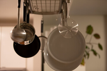 Kitchen with many pans and pots hanging on rack from the ceiling