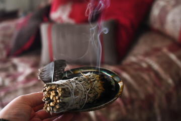 A close up image of a burning white sage smudge stick being used to smudge a room. 