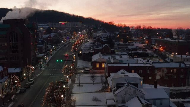 Aerial truck shot of ski resort town covered in winter snow at sunrise, sunset. Lights and Christmas holiday decorations.
