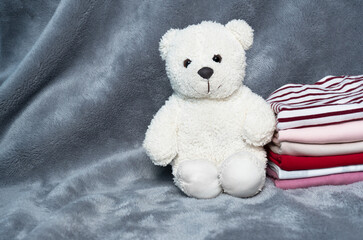 fluffy white small bear with cloth stack whit grey fur home laundry background