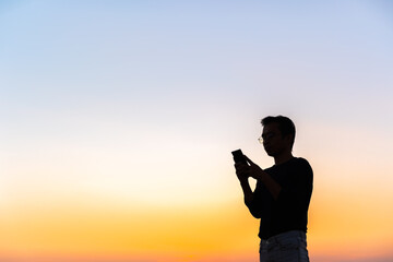Middle aged man using phone at sunset.A person looking down on a smartphone with copy space.