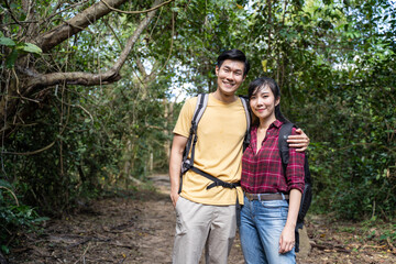 Portrait of Asian young backpacker couple travel through a forest.