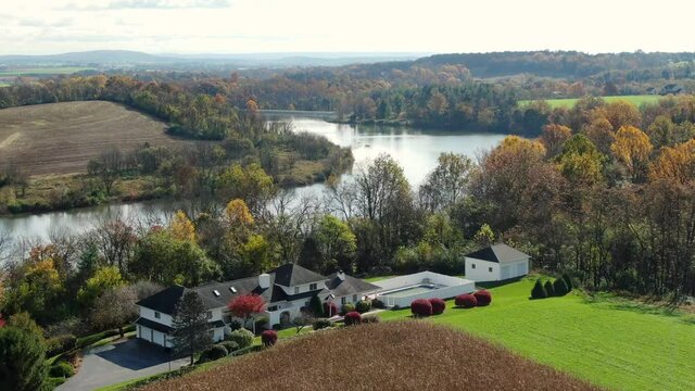 Large contemporary modern home, mansion overlooks river. Aerial view in autumn.