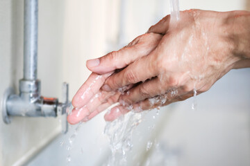 Hands of woman wash their hands in a sink with foam to wash the skin and water flows through the hands. Concept of health, cleaning and preventing germs and coronavirus from contacting hands