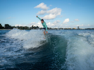 Athletic male rides crest of wave wearing long sleeve teal rashguard