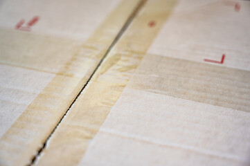 Criss crossing clear tape lines closing a white flat rate box for shipping in the mail