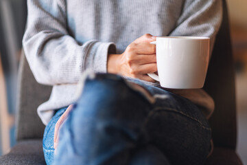 Closeup image of a woman holding a cup of coffee in cafe