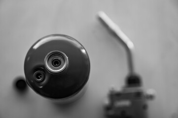 Selective focus on propane gas canister with blurred nozzle and head of blowtorch in the background