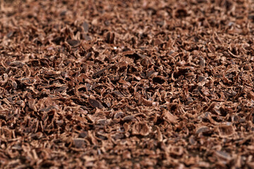 Grated dark chocolate. Chocolate flakes on brown table