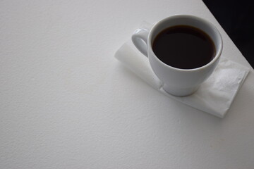 A small cup of black coffee on a white table top