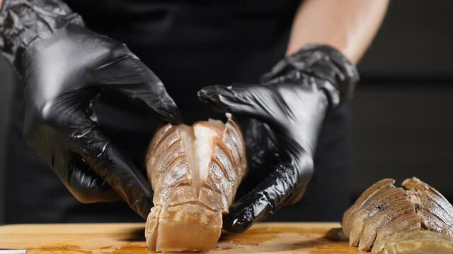 High end seafood restaurant concept. Mediterranean or Asian cuisine. Chef in black gloves opens grills lobster tail showing delicious meat. Slow motion. Serving food. Full hd
