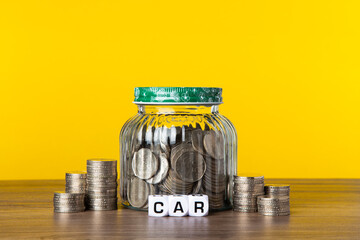 A lot coins in glass jar with yellow background. Saving for Car concept