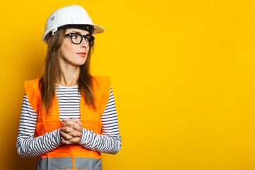 Young woman in a vest and hard hat on a yellow background. Construction concept, new building. Banner