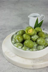 Putri mandi or badak berendam, Steamed glutinous rice with potato balls filled with green bean paste and serve with coconut milk. Selective focus