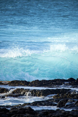 Blue waves braking by rocks 