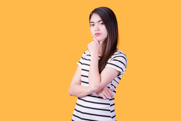 Smiling asian woman pointing up and looking at the camera over yellow background