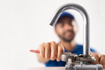 A BROKEN PIPE BEING FIXED BY A PLUMBER IN BACKGROUND	