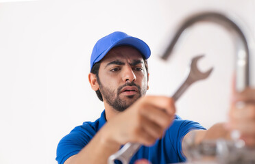 A PLUMBER LOOKING CONFUSED WHILE FIXING A BROKEN TAP	