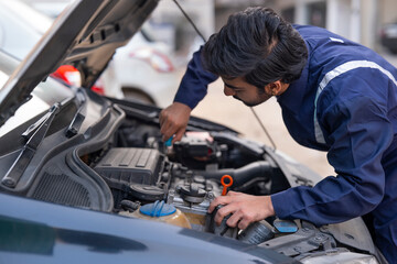 Fototapeta premium A YOUNG MECHANIC WORKING ON CAR ENGINE 