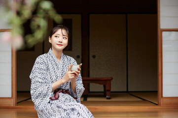 縁側でくつろぐ浴衣姿の若い女性