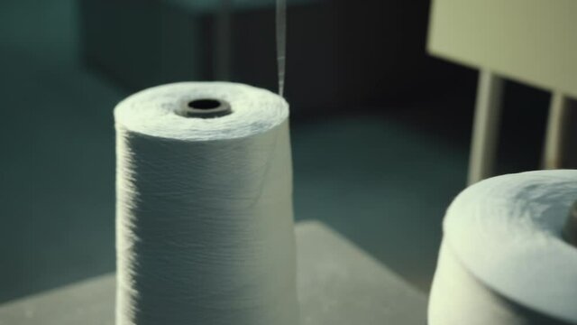 Row of textile threads industry. Spools white thread stand on a machine. Close-up spool threads in factory. Cotton yarn for spinning