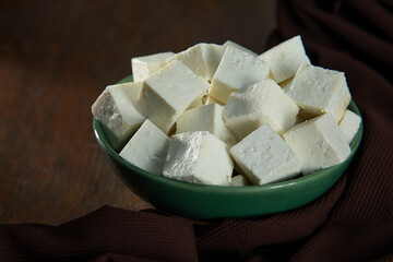 Diced Paneer or cottage cheese in a green bowl	