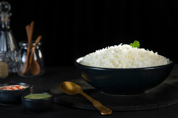 Steamed rice in a black bowl with green chutney and curd	