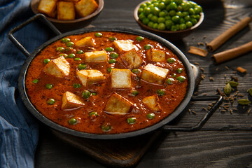 Mattar Paneer or cottage cheese with Peas. A vegetarian Indian delicacy, with raw peas and fried paneer (cottage cheese) in the background. 	